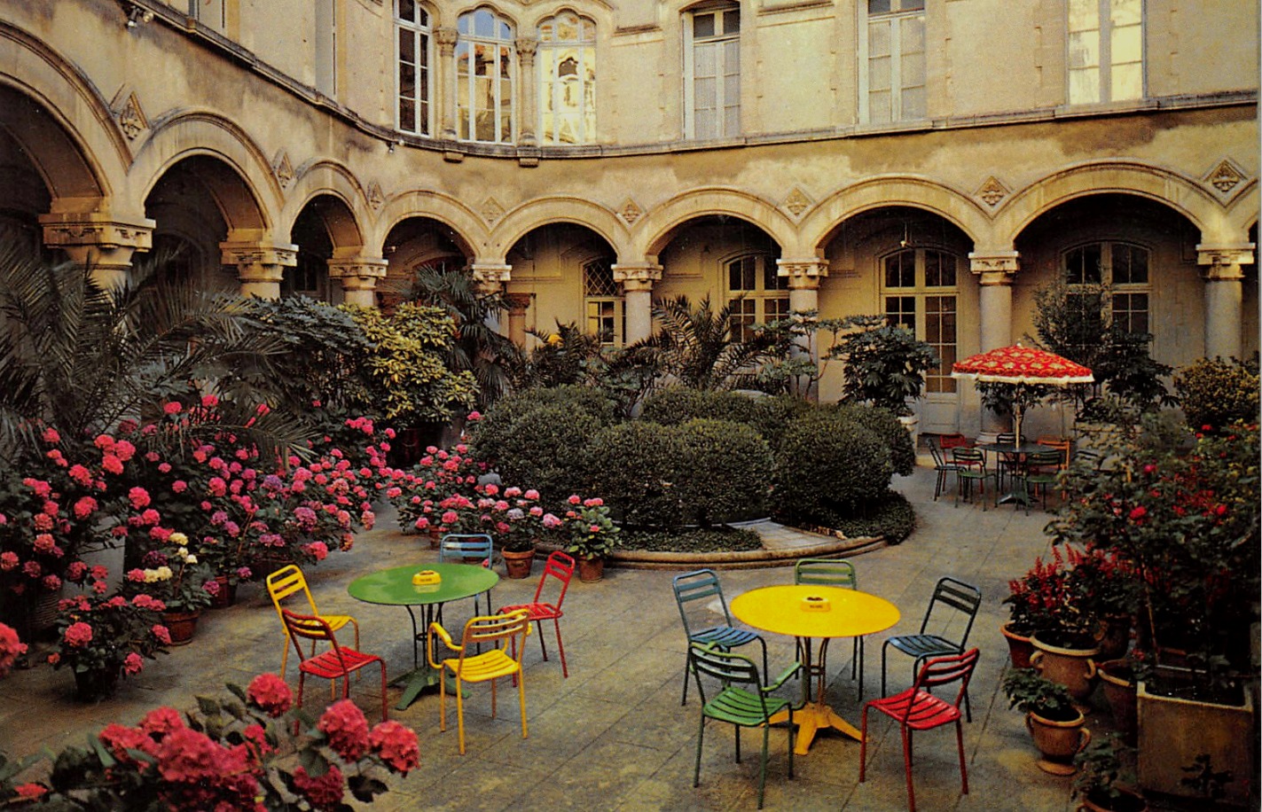 Photo d'archive du cloître intérieur du bâtiment de l'école, avec hortensias et mobilier de bistrot